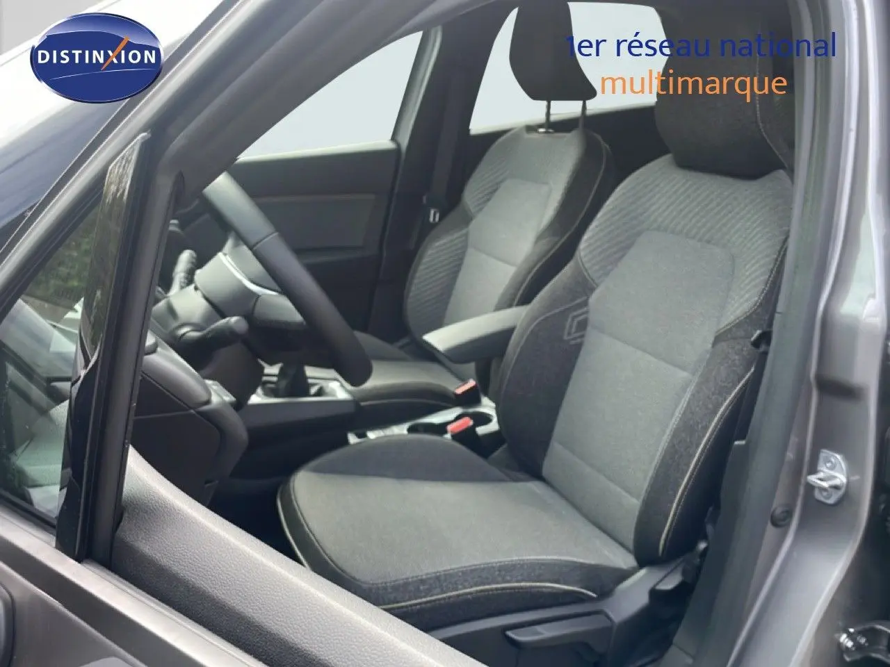 Vue intérieure côté conducteur du Renault Captur gris Cassiopée métal, montrant les sièges en tissu gris et le volant multifonction.