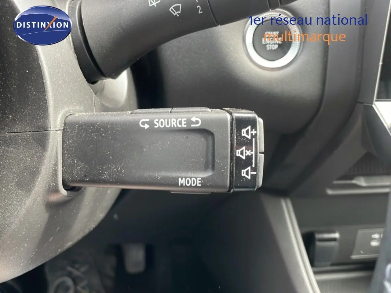 Gros plan sur la commande multimédia au volant du Renault Captur 2025, intérieur gris noir avec bouton start/stop visible.