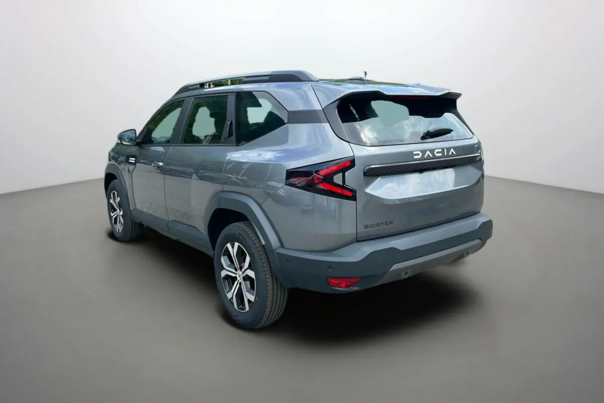 Vue 3/4 arrière droite du SUV Dacia Bigster gris schiste avec barres de toit et jantes alu 17 pouces.