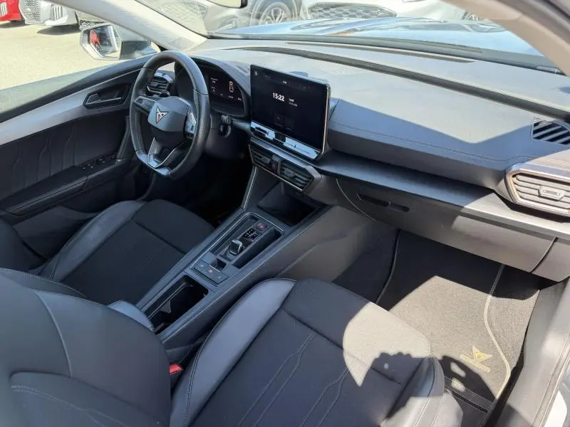 Intérieur avant droit de la CUPRA Formentor 1.4 e-HYBRID 2024 avec volant sport, écran tactile et sellerie noire.