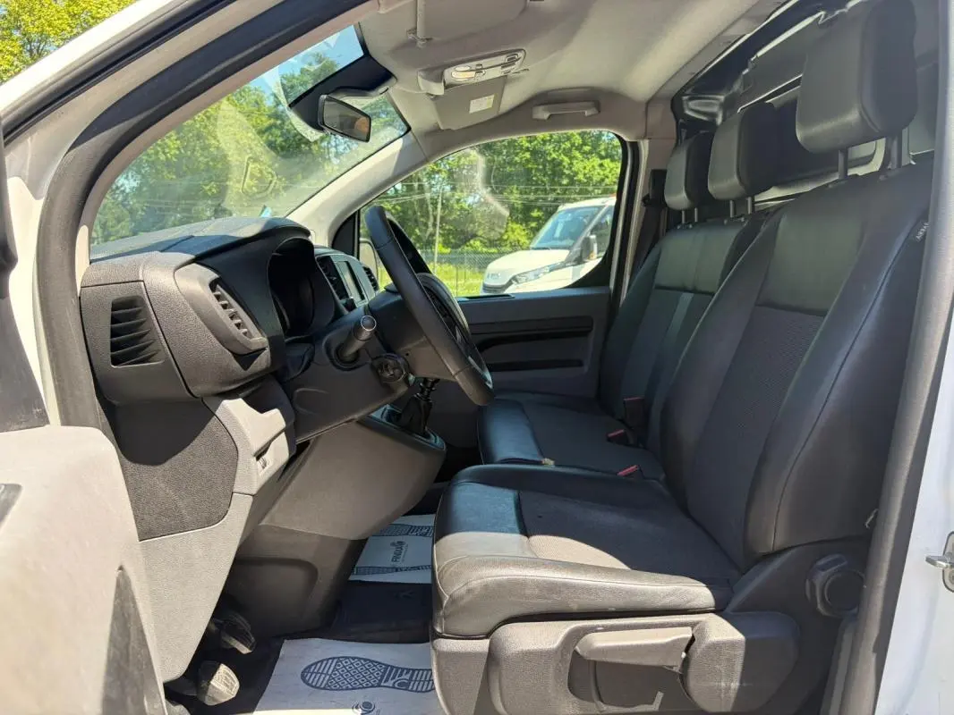 Vue intérieure côté conducteur du Peugeot Expert Fourgon blanc 2019, montrant les sièges en cuir et le volant multifonctions.