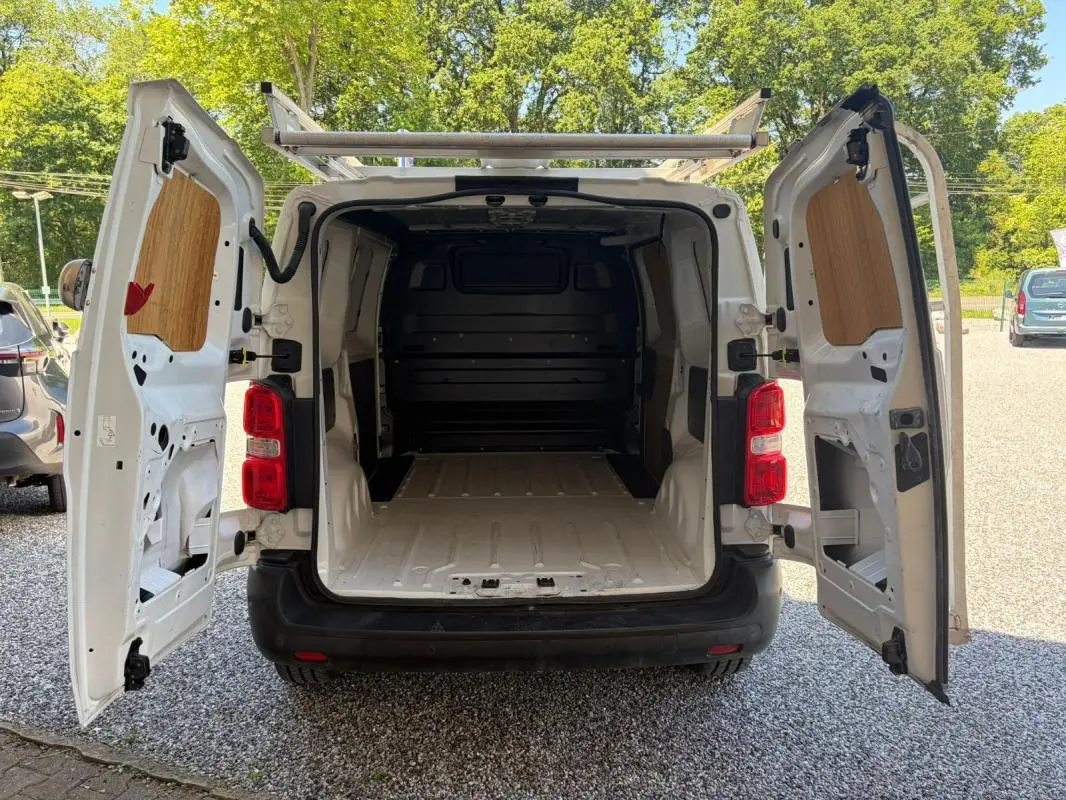 Vue arrière ouverte du Peugeot Expert Fourgon blanc L1H1 Confort 2019, montrant l’espace de chargement vide et la galerie sur le toit.