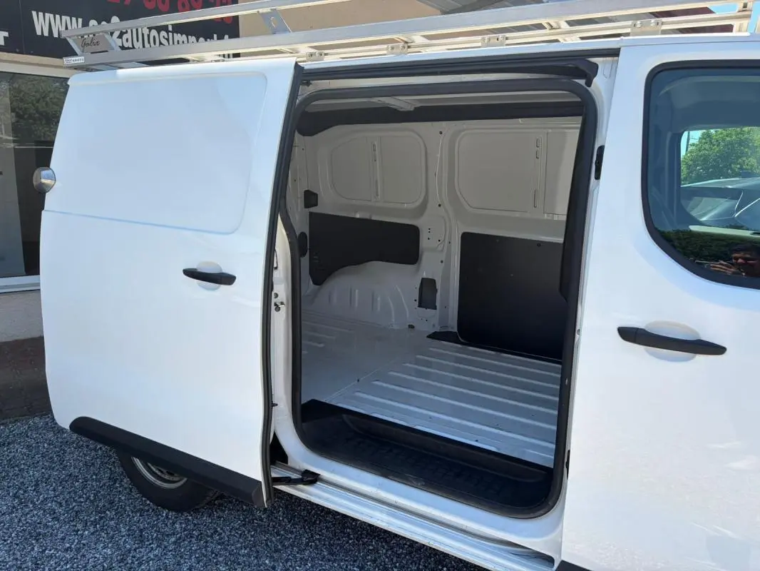 Vue latérale gauche d’un Peugeot Expert Fourgon blanc avec porte coulissante ouverte montrant l’espace de chargement vide.