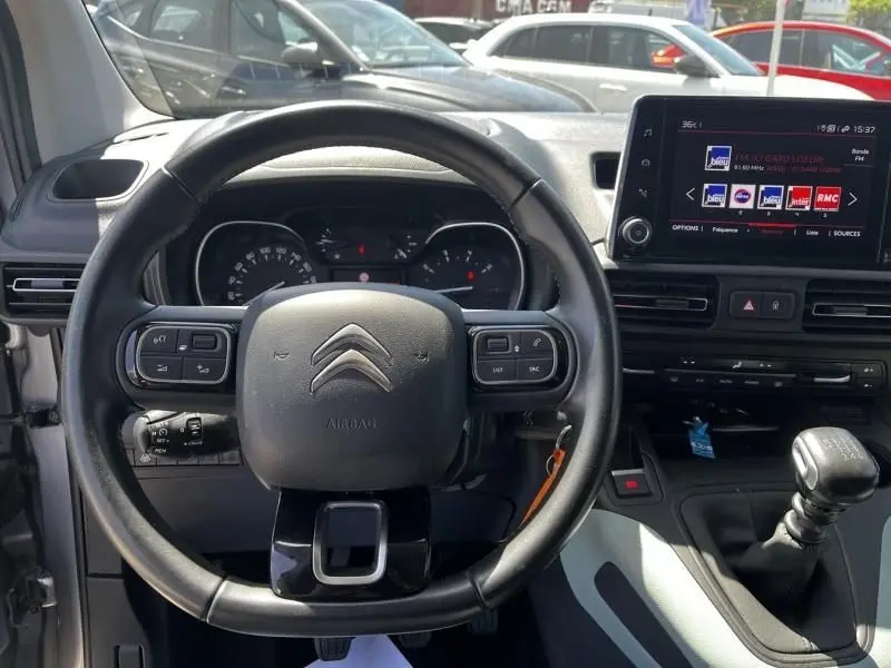 Vue intérieure centrée sur le volant noir du Citroën Berlingo gris métal 2021 avec tableau de bord et écran tactile visible.