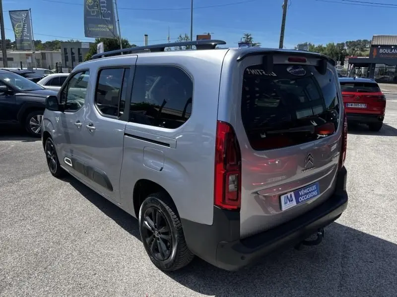Vue 3/4 arrière droite d'un Citroën Berlingo XL gris métal 2021 avec vitres teintées et jantes noires.