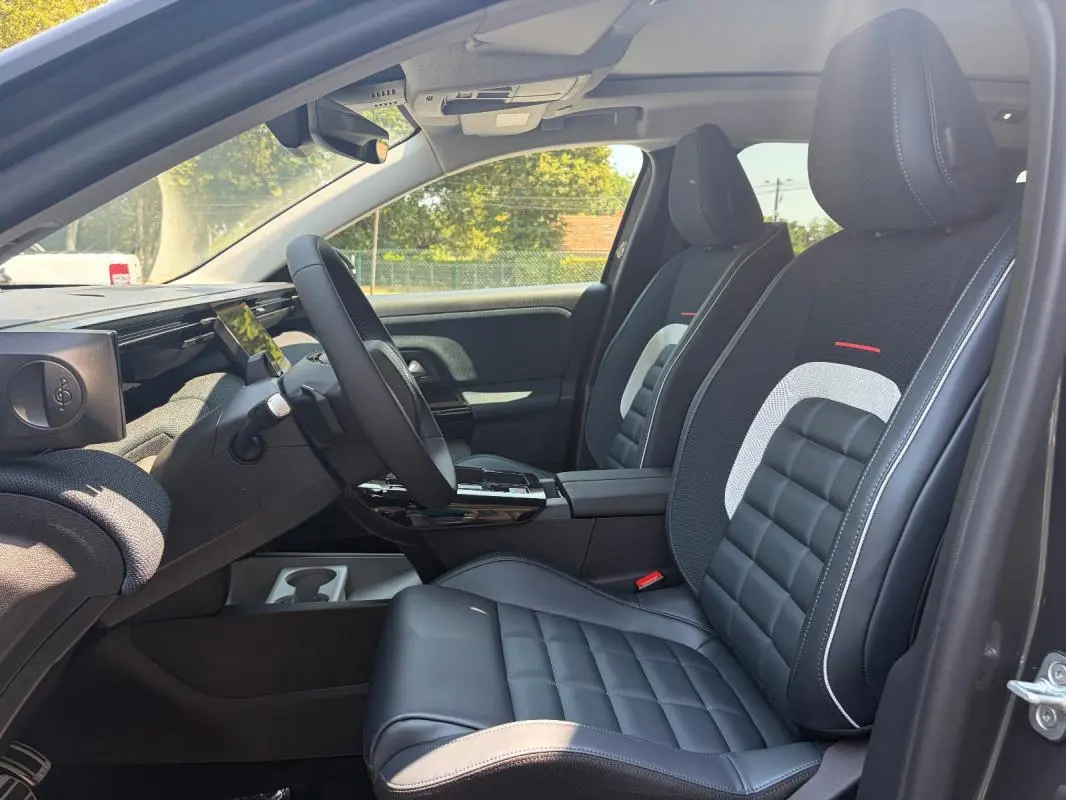 Vue intérieure côté conducteur du Citroën C5 Aircross gris 2026, sièges cuir noir avec surpiqûres blanches et volant multifonctions.