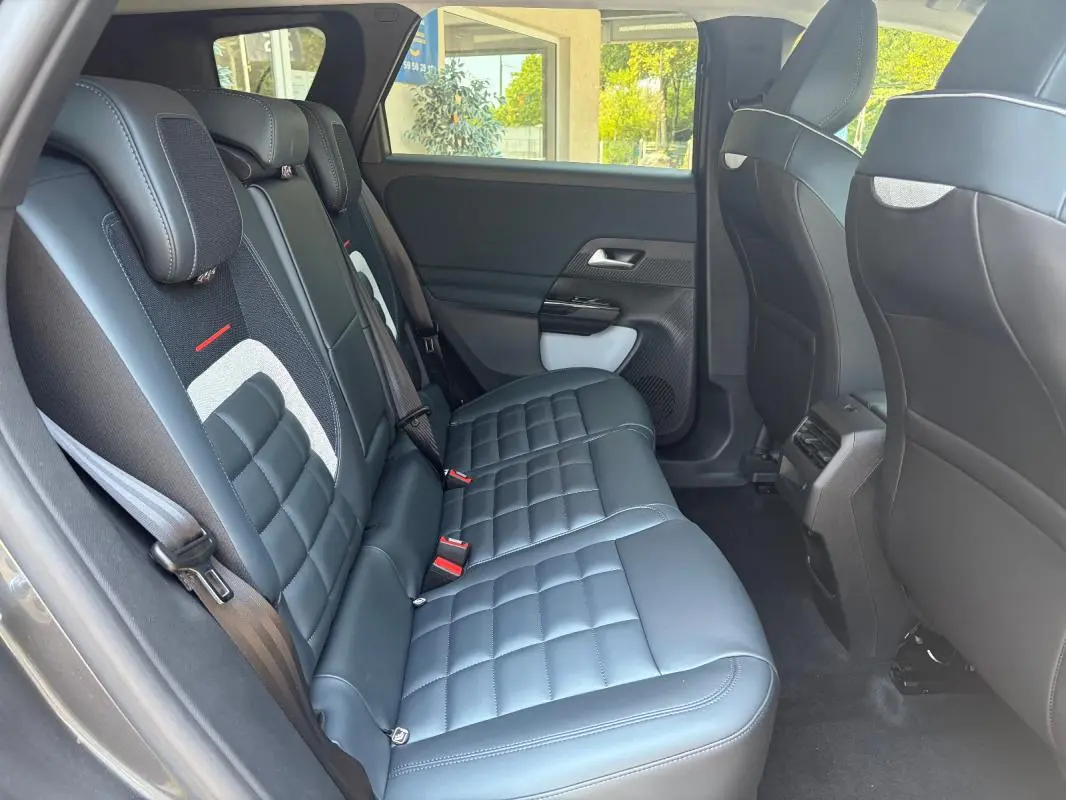 Vue intérieure côté gauche de la banquette arrière en cuir noir du Citroën C5 Aircross gris avec appuie-têtes et ceintures visibles.