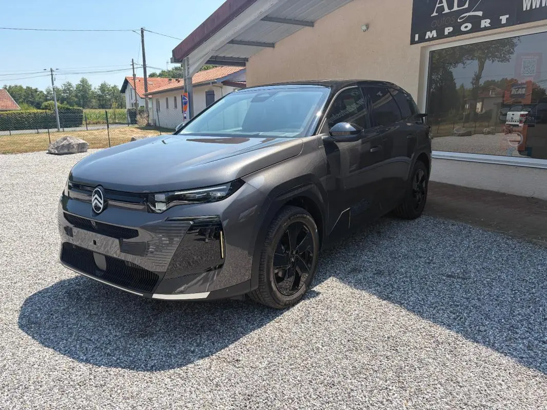 Vue 3/4 avant d’un Citroën C5 Aircross gris 2026 avec jantes noires et toit ouvrant panoramique visible.