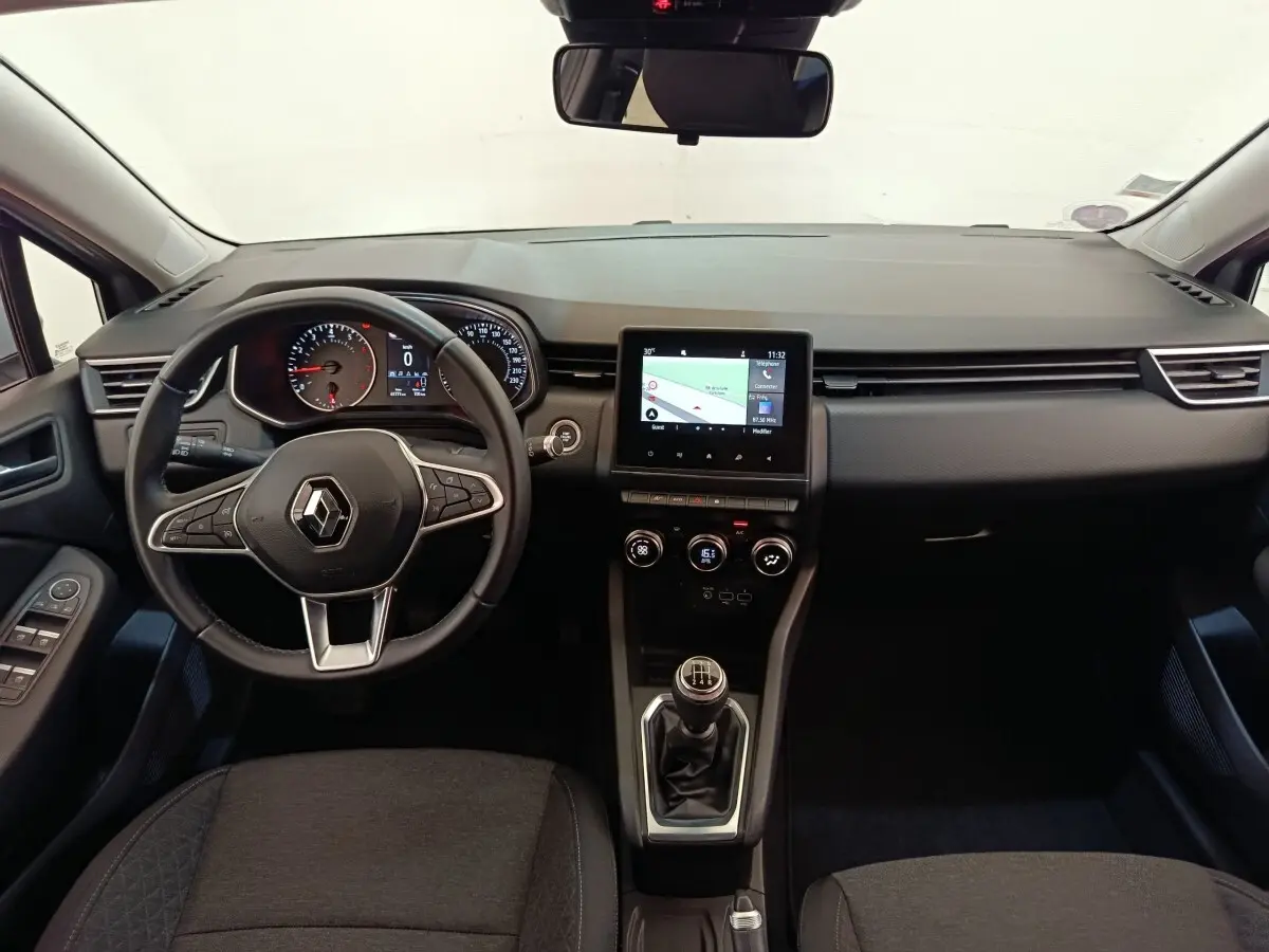 Vue intérieure frontale de la Renault Clio Business TCe 100 2021, tableau de bord noir avec écran tactile et volant multifonctions cuir.
