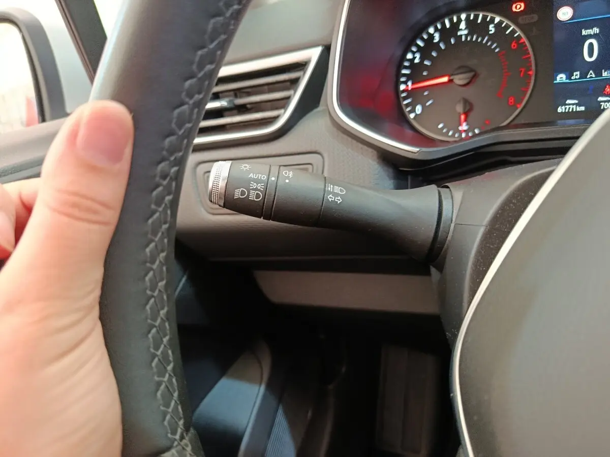 Gros plan sur le volant cuir synthétique et la manette des phares dans le tableau de bord de la Renault Clio Business gris clair.