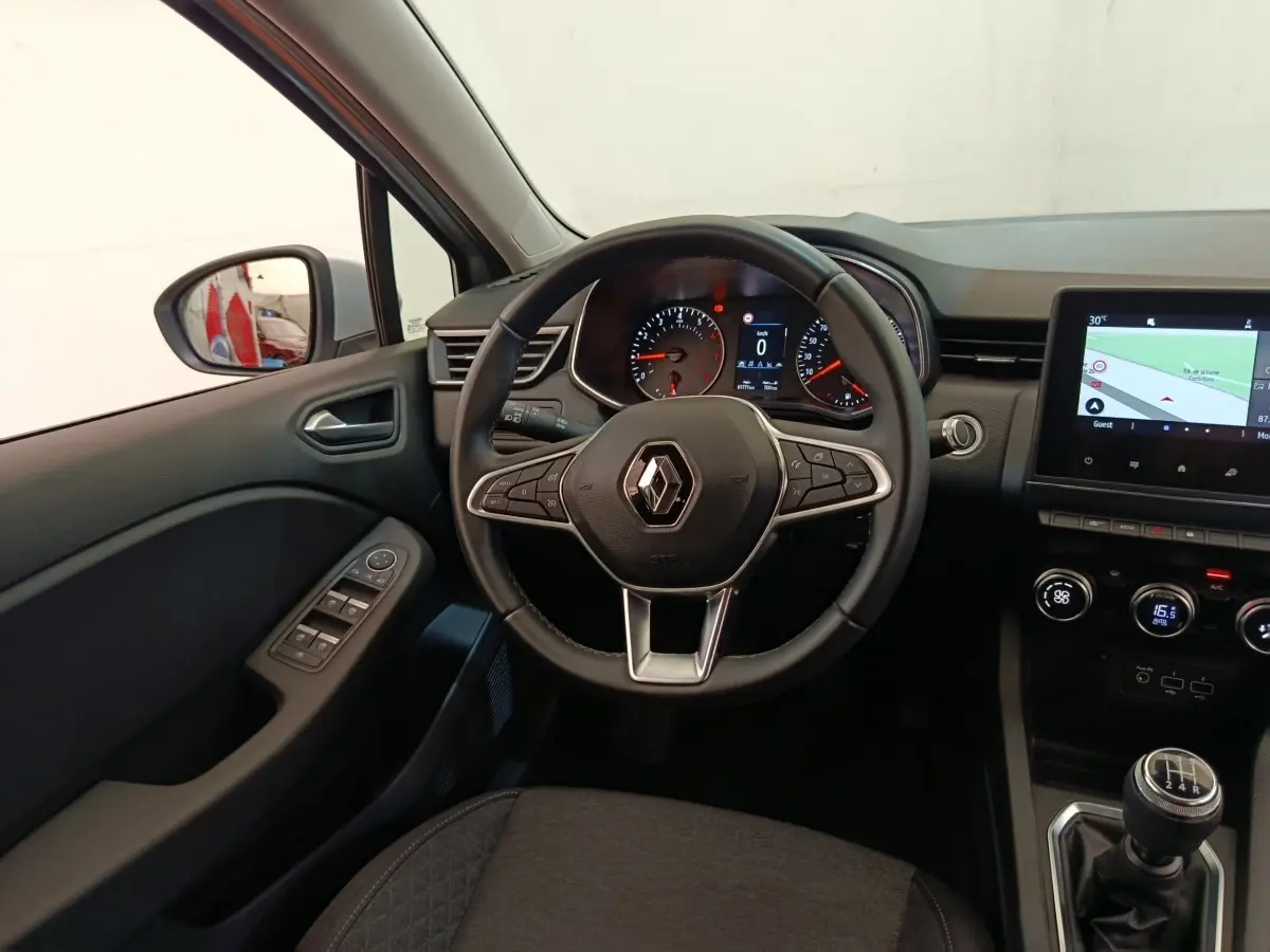 Vue intérieure centrée sur le volant cuir multifonctions et tableau de bord avec écran tactile de la Renault Clio gris clair.