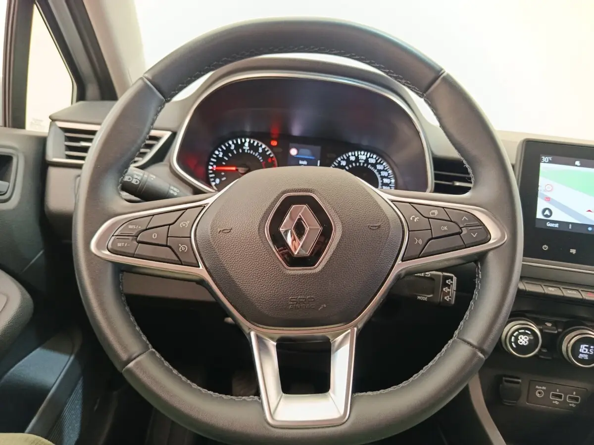 Vue rapprochée du volant cuir multifonctions de la Renault Clio Business TCe 100, avec tableau de bord et écran tactile visibles.