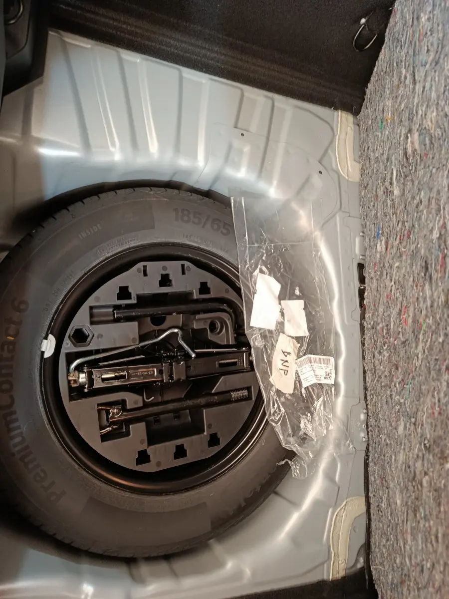 Vue rapprochée de la roue de secours et des outils dans le coffre gris clair d’une Renault Clio Business TCe 100 2021.