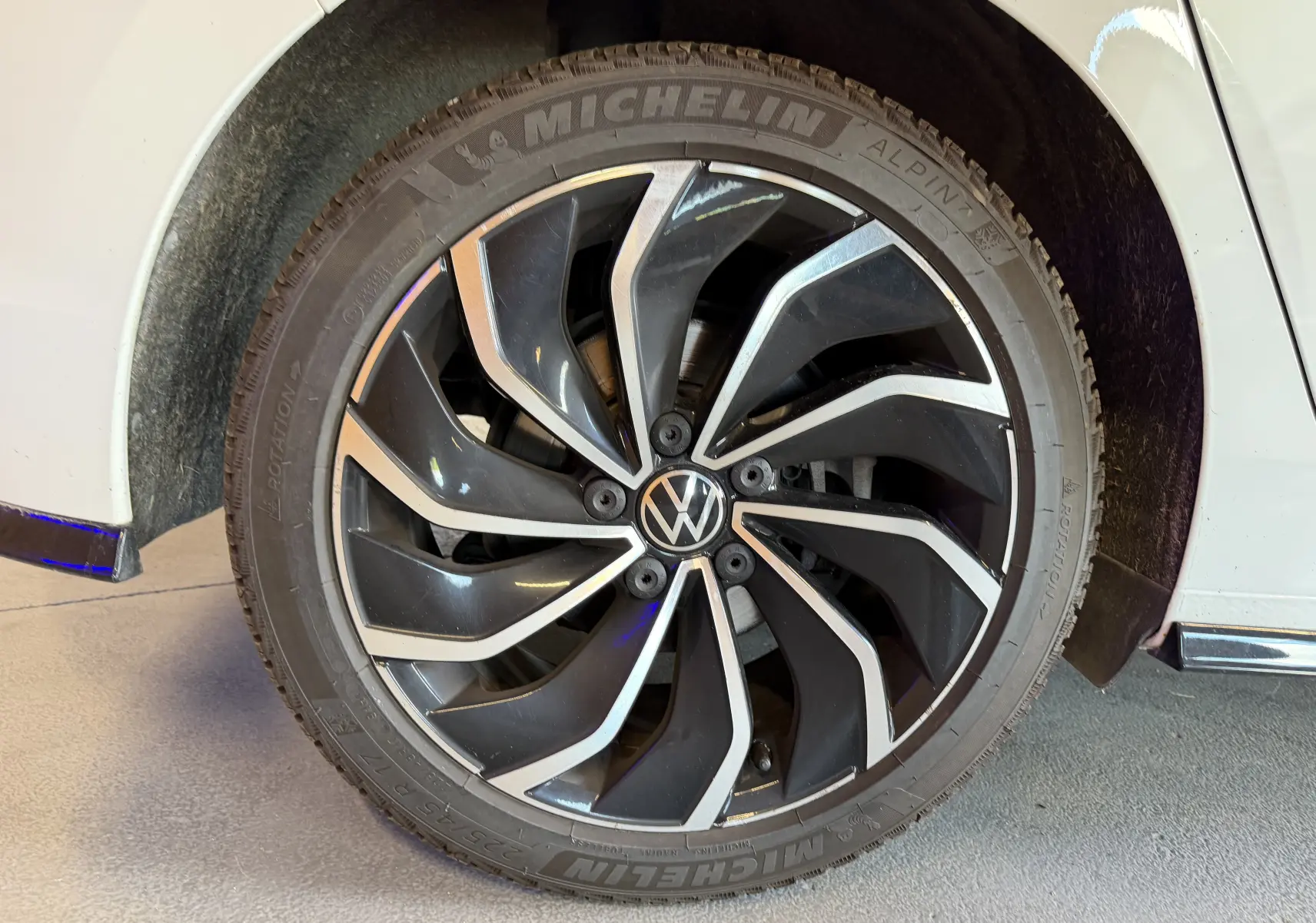 Gros plan sur la jante avant droite noire et argentée d'une Volkswagen Golf 2.0 TDI 150 DSG7 R-Line blanche.