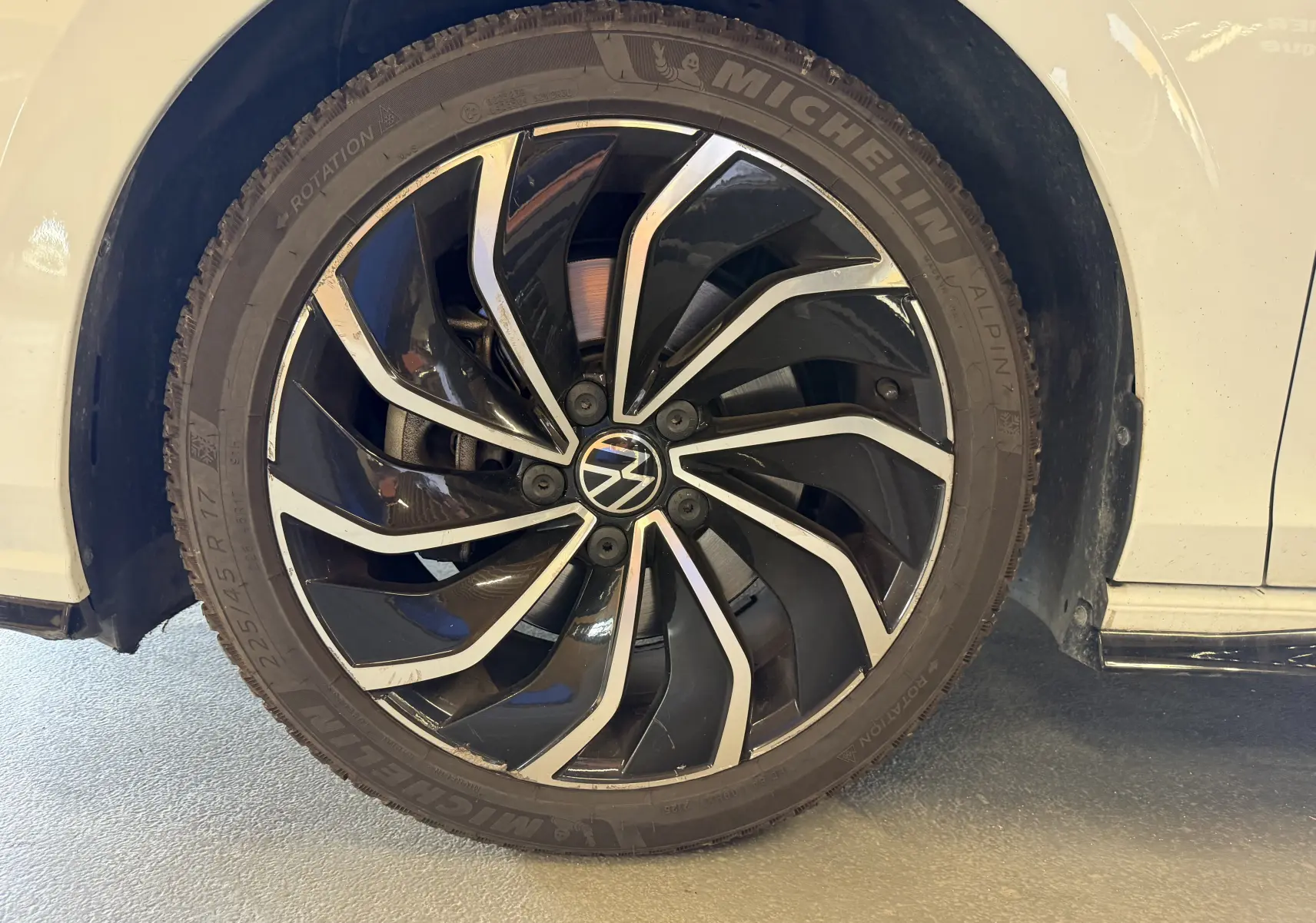 Gros plan sur la roue avant gauche d'une Volkswagen Golf 2.0 TDI blanche, jante alliage noir et argent R-Line.