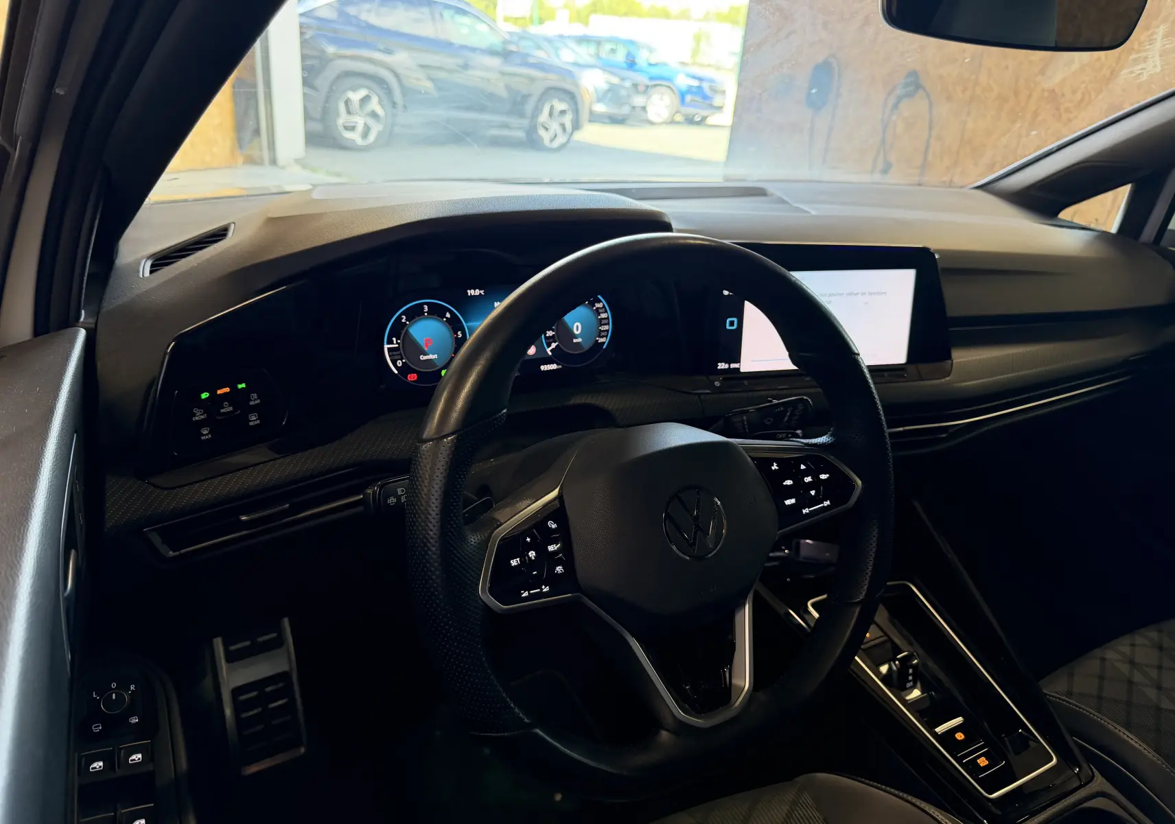Vue intérieure du poste de conduite de la Volkswagen Golf 2.0 TDI 150 DSG7 R-Line, tableau de bord digital et volant multifonction noir.