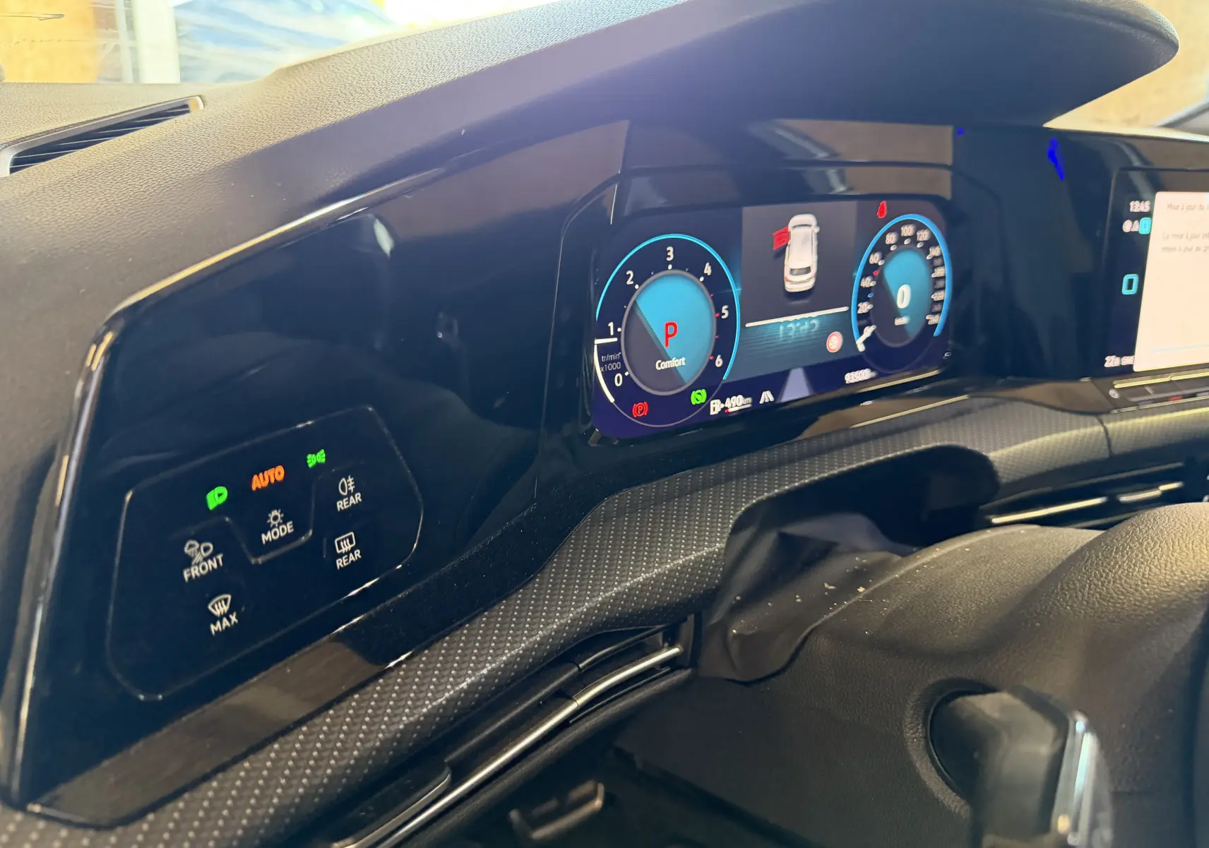 Vue rapprochée du tableau de bord numérique et des commandes d’éclairage sur la gauche dans une Volkswagen Golf blanche 2023.