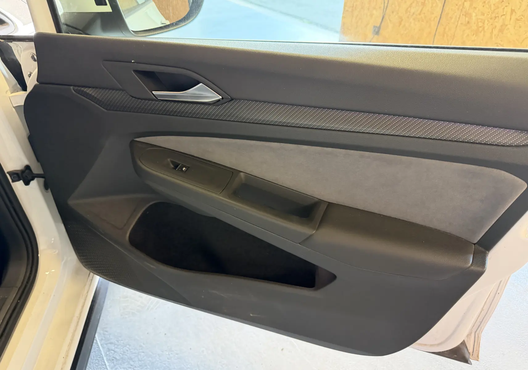 Vue intérieure côté gauche de la porte avant blanche de la Volkswagen Golf 2.0 TDI R-Line avec garniture noire et grise.