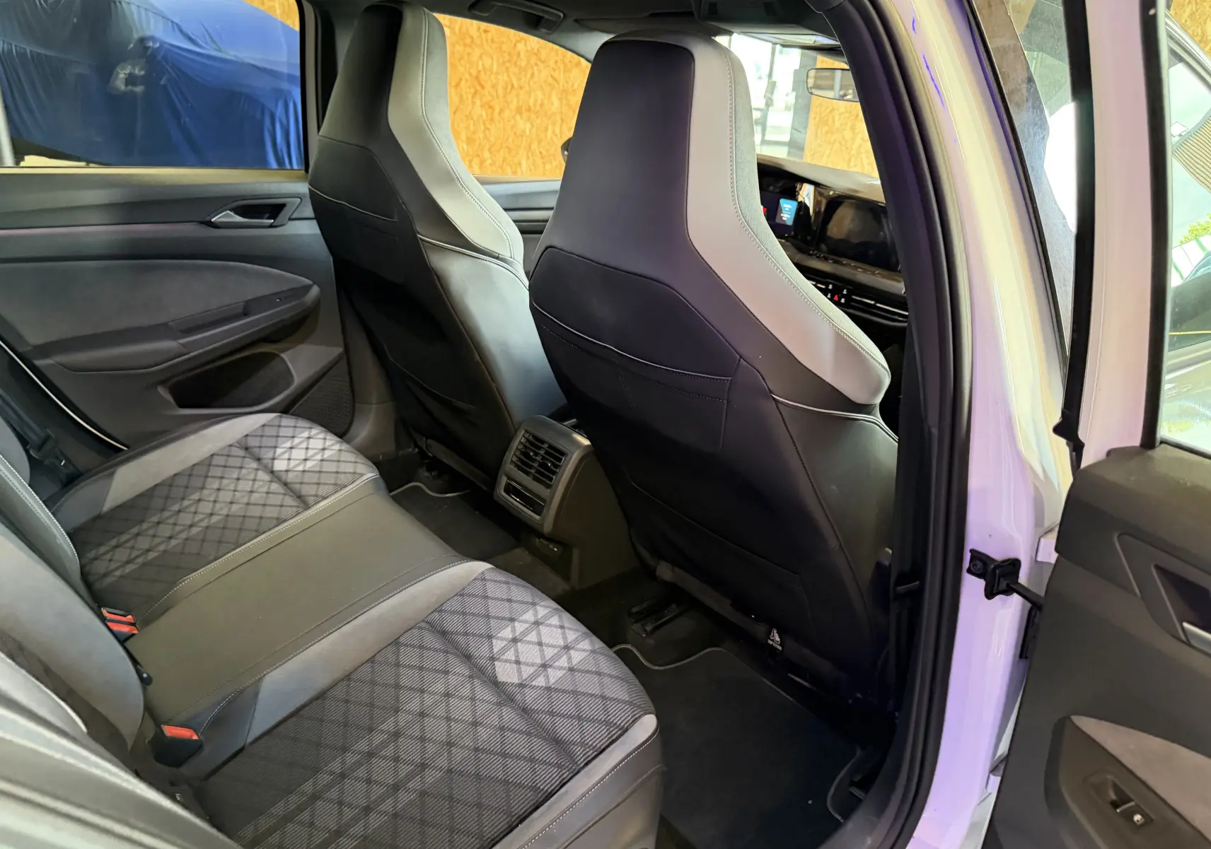 Vue intérieure arrière droite d'une Volkswagen Golf blanche 2023, sièges arrière en tissu et cuir noir avec motifs géométriques.