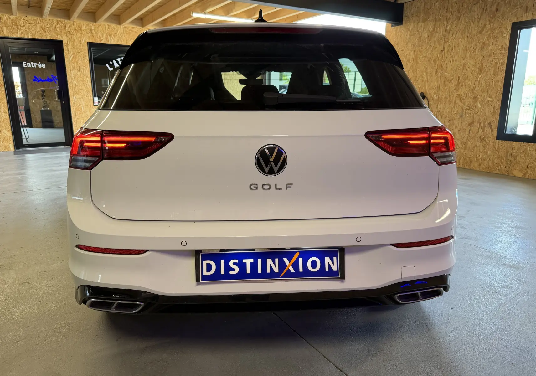 Vue arrière d'une Volkswagen Golf 2.0 TDI R-Line blanche de 2023, avec feux arrière allumés et double sortie d'échappement.