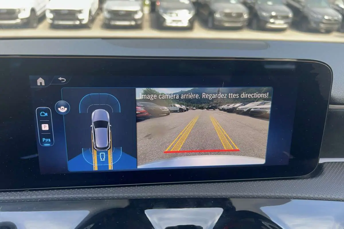 Écran intérieur de la Mercedes Classe A 200 AMG Line 2025 montrant la caméra de recul avec lignes de guidage jaunes et rouges.