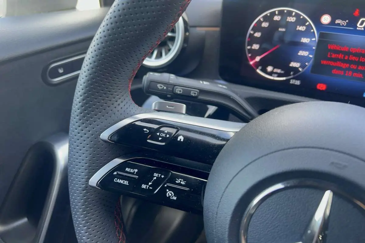 Gros plan sur le volant cuir perforé avec commandes multifonctions et tableau de bord digital de la Mercedes Classe A AMG Line 2025.