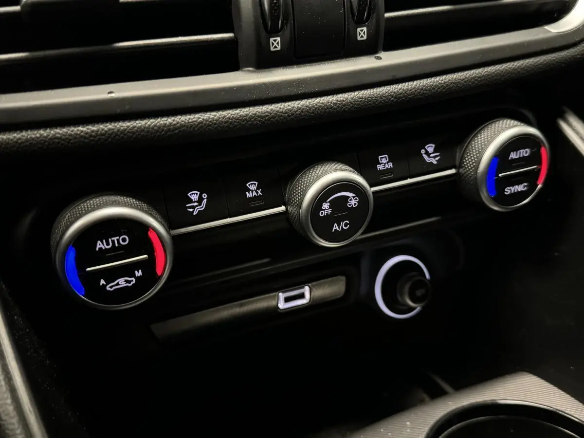 Gros plan sur la console centrale de l'Alfa Romeo Giulia 2021, montrant les commandes de climatisation automatique à réglages colorés.