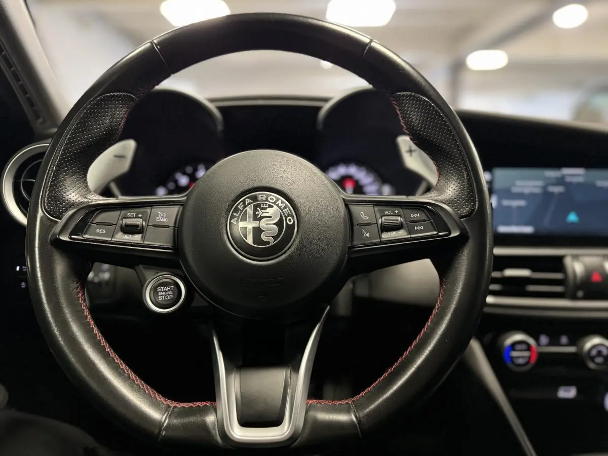 Vue frontale du volant cuir noir de l'Alfa Romeo Giulia 2.2 D 190 BVA Super avec palettes aluminium brossé.