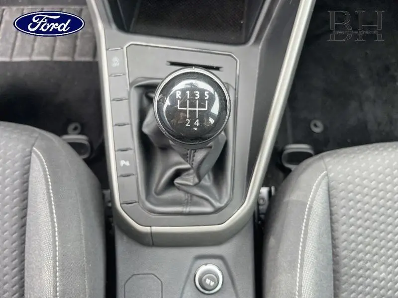 Le levier de vitesses manuel noir vu de dessus entre deux sièges gris dans l'habitacle d'une Volkswagen Polo blanche