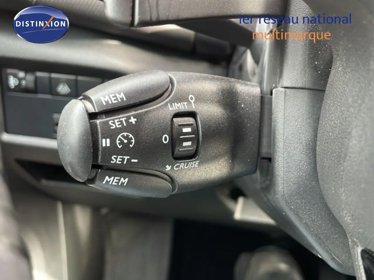 Gros plan sur la commande de régulateur de vitesse à gauche du volant dans l’habitacle noir du Citroën C5 Aircross bleu Eclipse Metal.