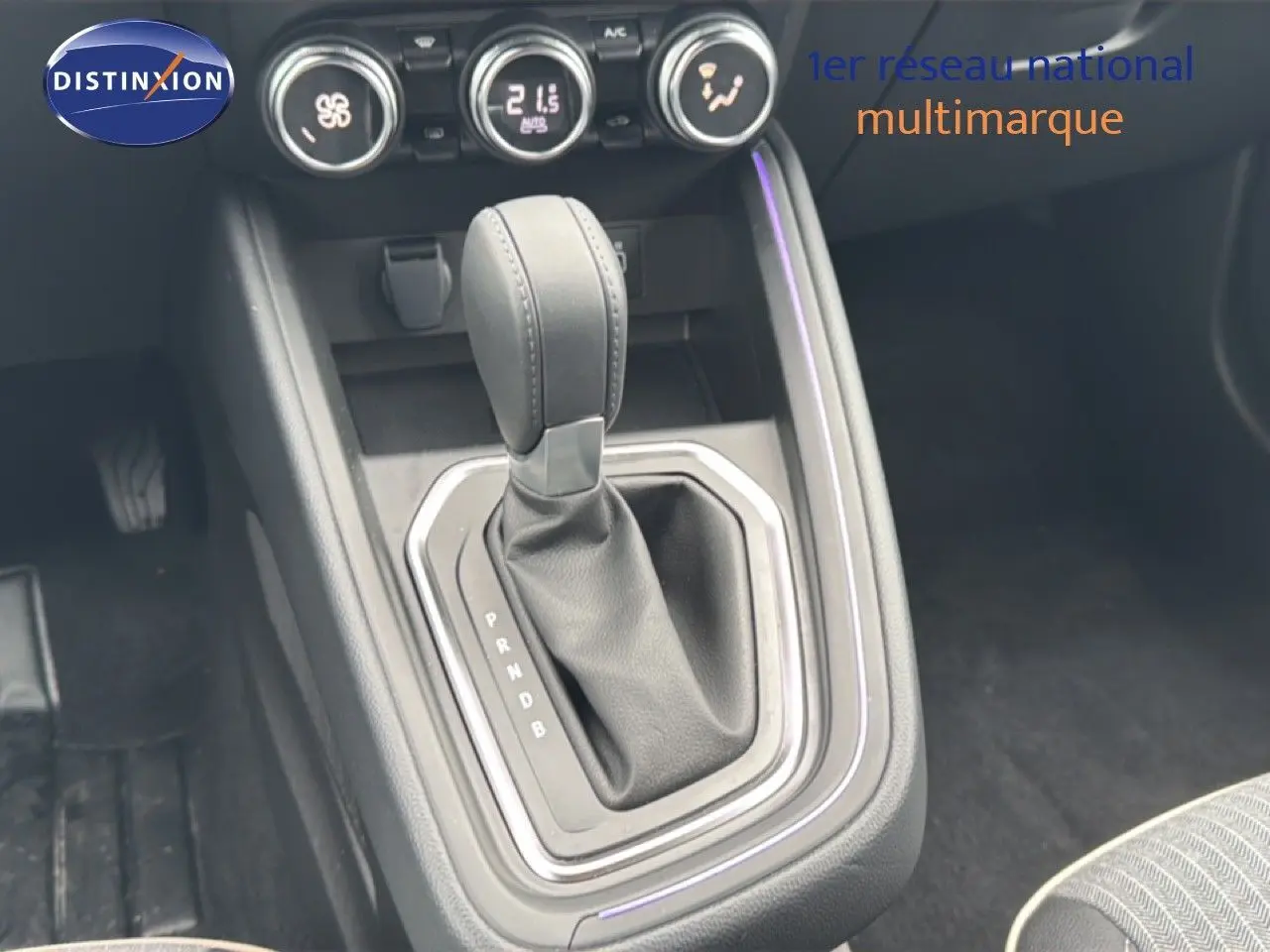 Gros plan sur la console centrale de la Renault Clio 2025, boîte automatique, avec levier en cuir noir et commandes de climatisation.