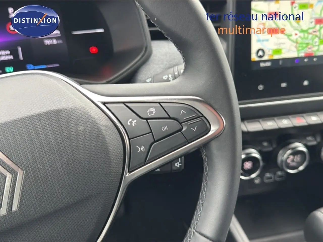 Gros plan sur le volant à droite de la Renault Clio 2025, avec commandes intégrées et tableau de bord numérique en arrière-plan.