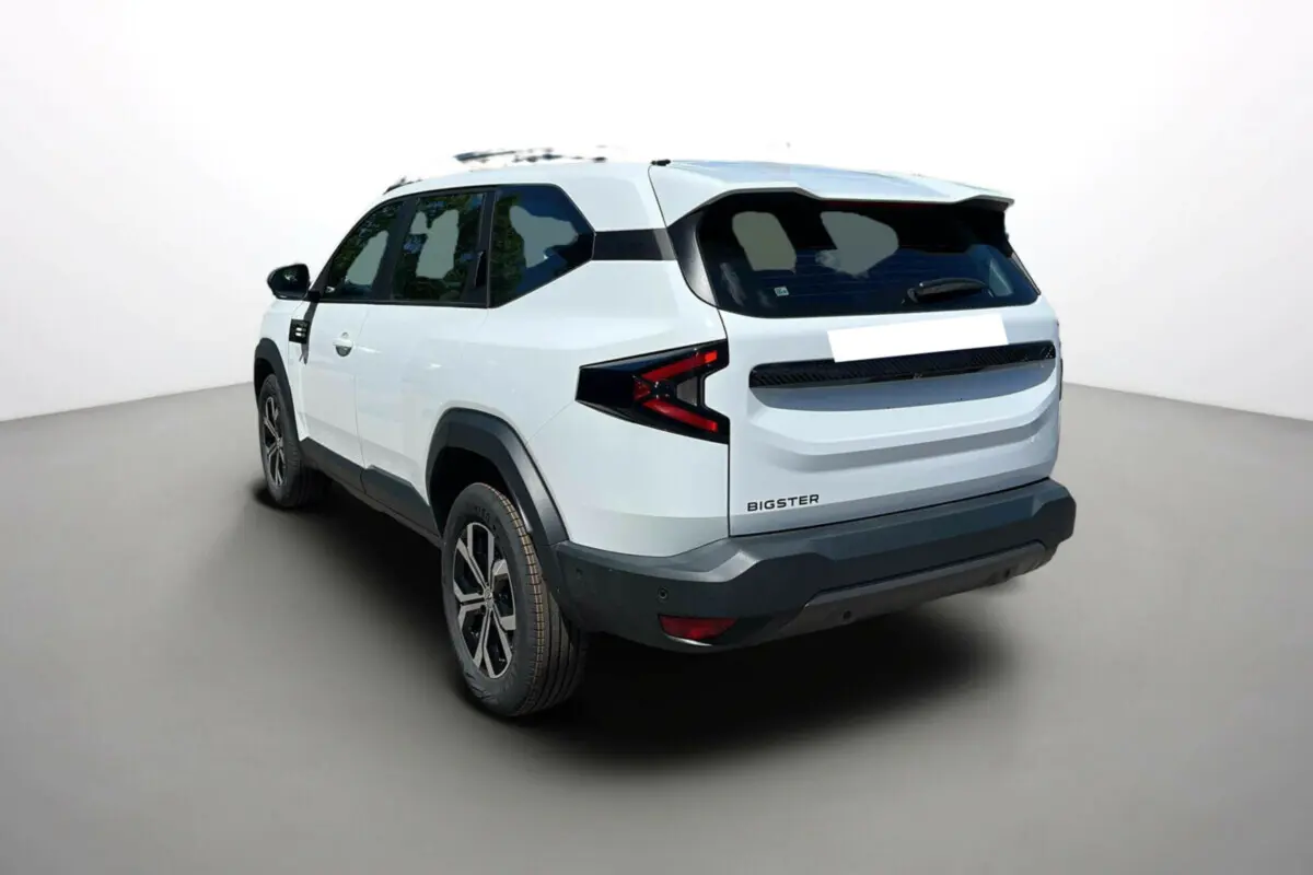 Vue 3/4 arrière droite du Dacia Bigster blanc glacier, avec barres de toit et jantes alu 17 pouces visibles.