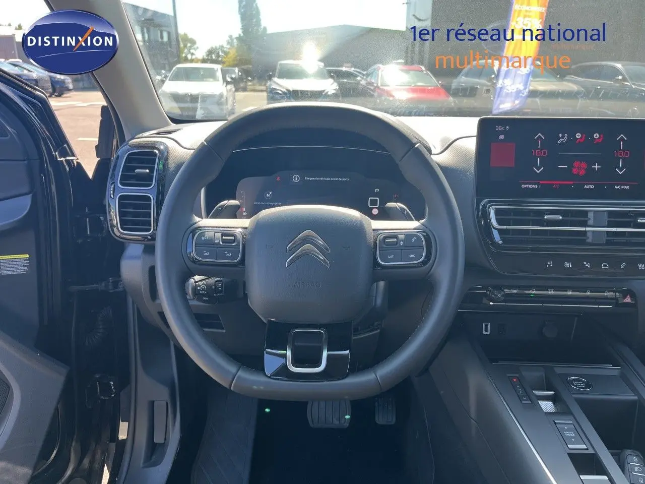 Vue intérieure centrée sur le volant noir du Citroën C5 Aircross 2025, avec tableau de bord digital et écran tactile.