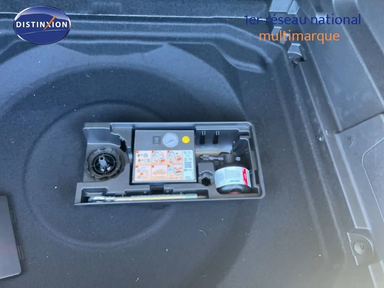 Compartiment de coffre noir avec kit de réparation pneus intégré dans un Citroën C5 Aircross 2025 hybride.