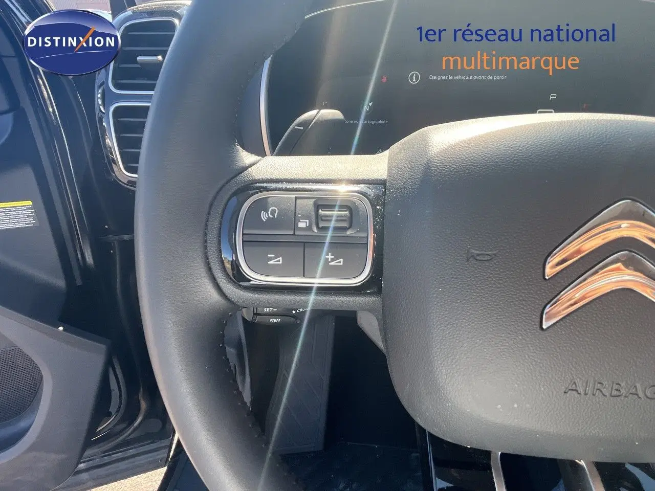 Gros plan sur le volant noir cuir du Citroën C5 Aircross 2025, avec commandes intégrées et logo chrome visible.