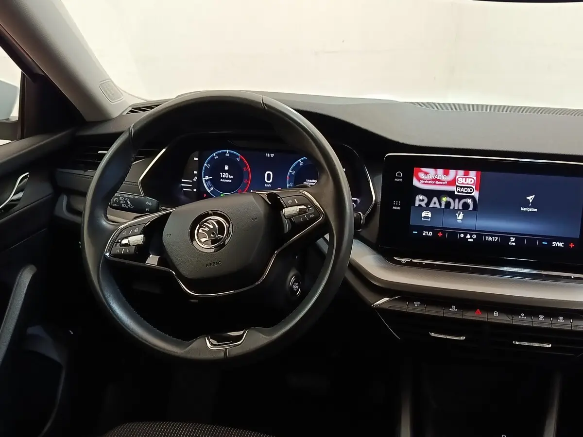 Vue intérieure centrée sur le volant cuir et alu multifonctions de la Skoda Octavia 2023 avec tableau de bord numérique et écran tactile.