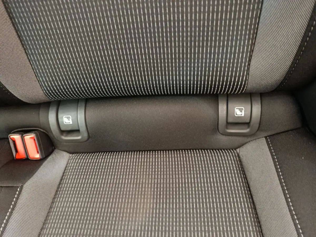 Gros plan sur la banquette arrière noire à motifs rayés avec attaches Isofix et boucles de ceinture rouges.