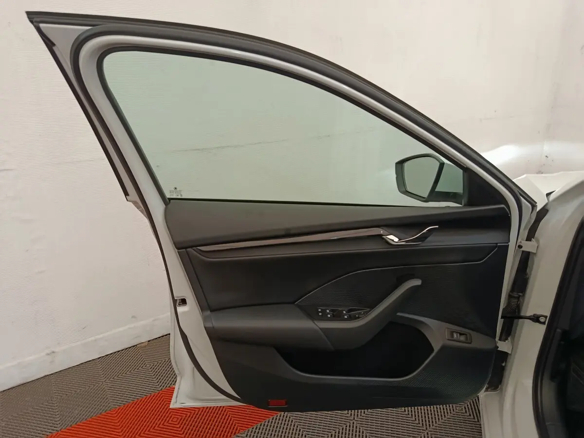 Vue intérieure de la porte avant gauche blanche d'une Skoda Octavia 2023 avec garniture noire et commandes électriques.