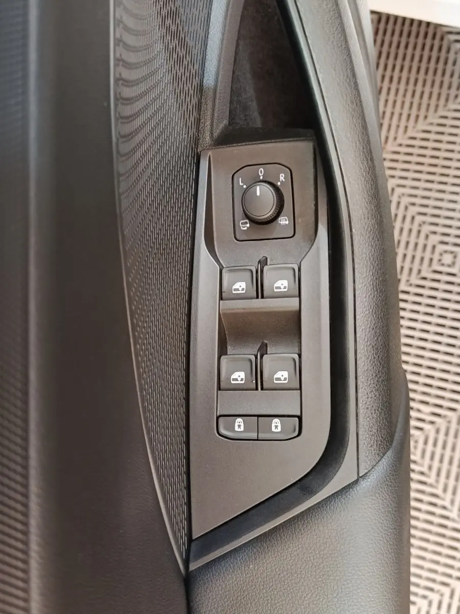 Gros plan sur les commandes de réglage des rétroviseurs et vitres côté conducteur d'une Skoda Octavia blanche 2023.