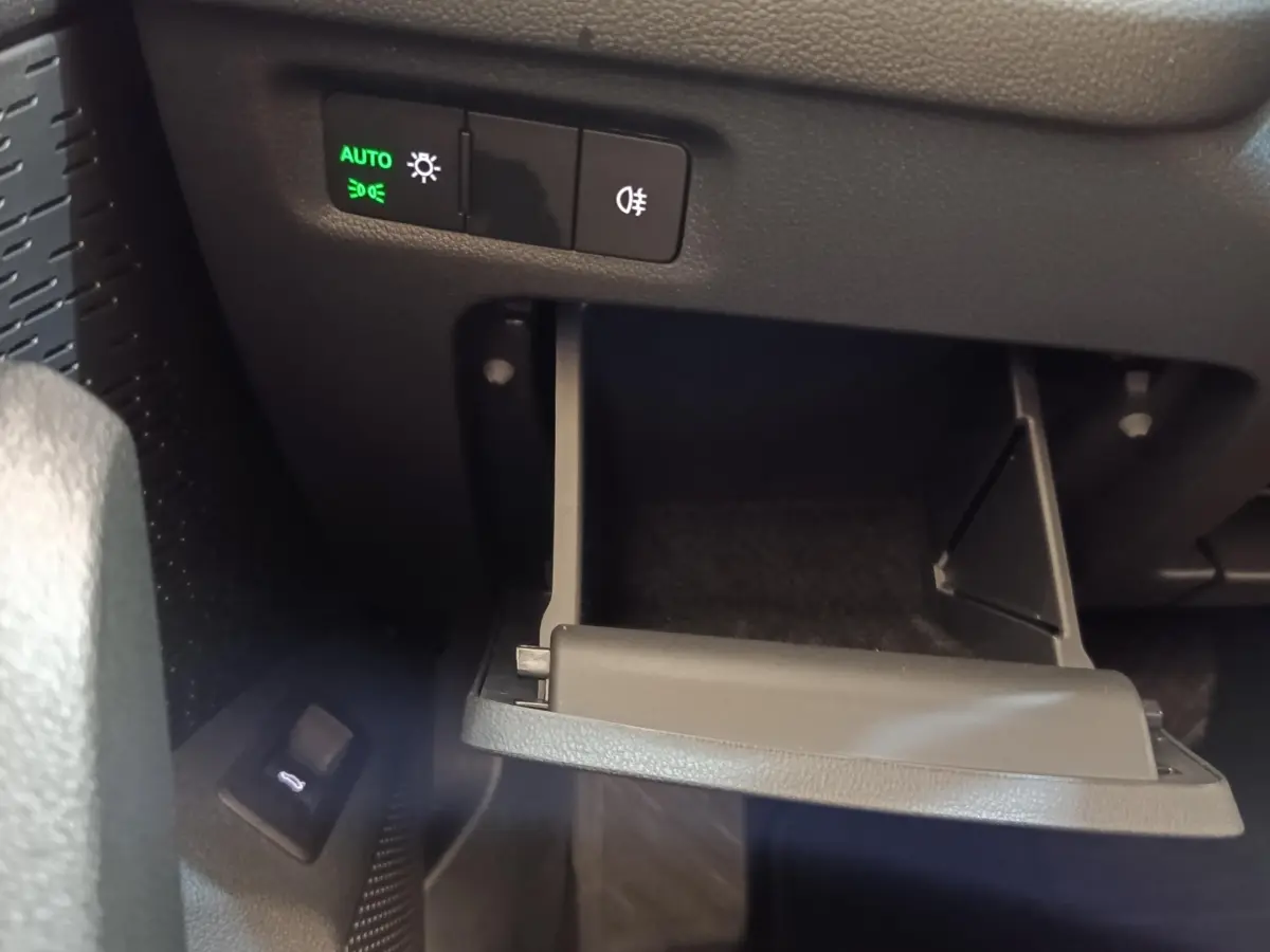 Détail intérieur montrant le tiroir ouvert sous le tableau de bord avec commandes d'éclairage sur une Skoda Octavia 2023.