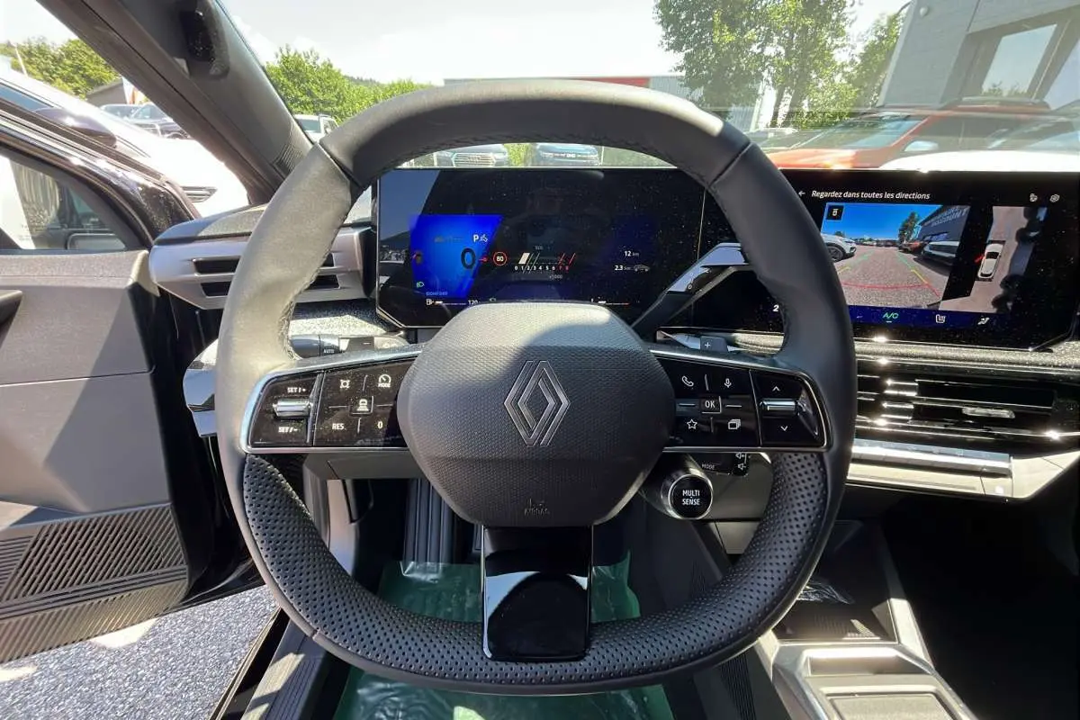 Vue centrée sur le volant noir perforé de la Renault Clio 6 TCE 115 EDC avec tableau de bord numérique et écran tactile.