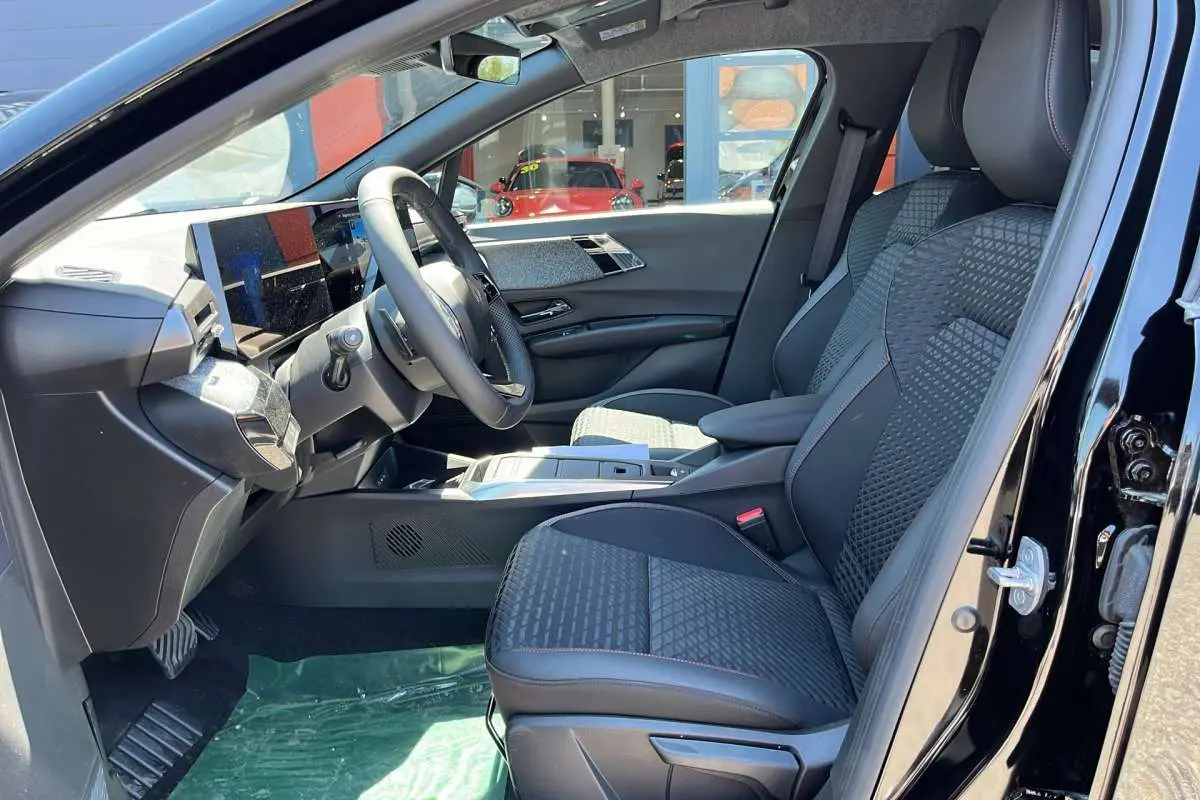 Vue intérieure côté conducteur de la Renault Clio 6 TCE 115 EDC Techno Plus noire étoilée, sièges avant en tissu et cuir.