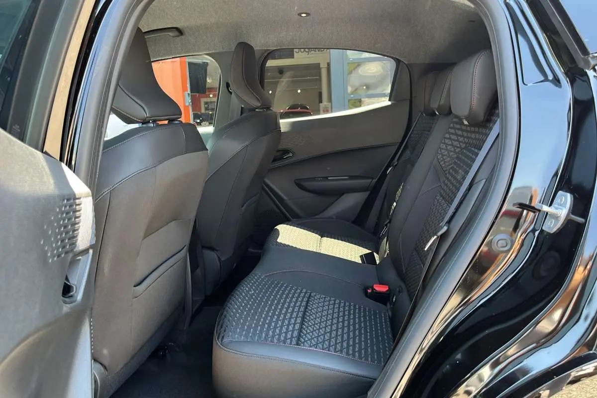 Vue côté gauche de l’intérieur arrière de la Renault Clio noir étoilé, sièges avec motif géométrique et surpiqûres rouges.