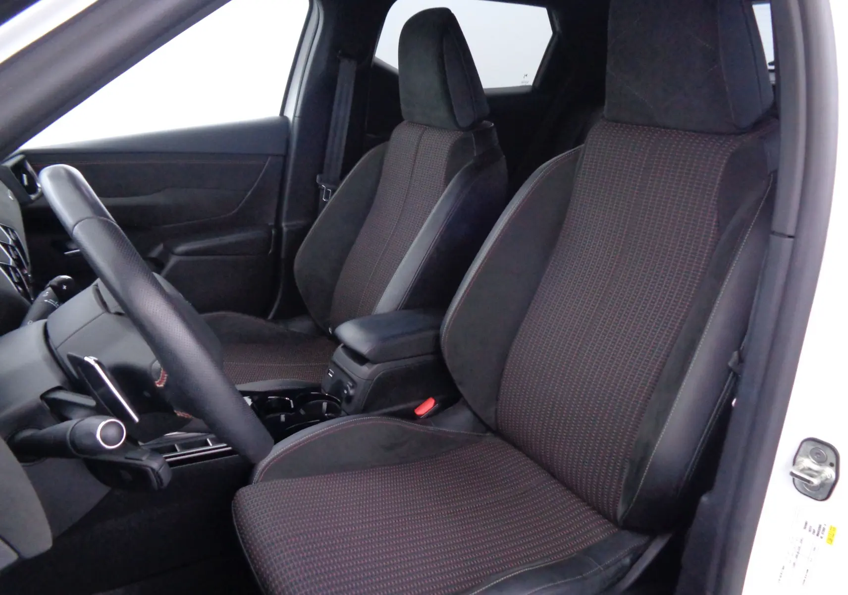 Vue intérieure côté gauche du DS3 Crossback 2021, sièges tissu noir à motifs rouges avec volant cuir perforé.