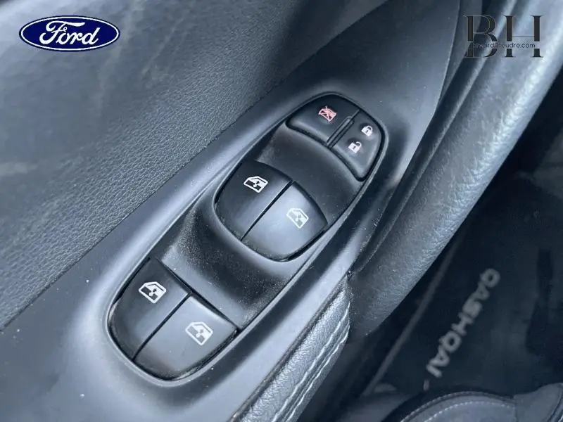 Gros plan sur les commandes des vitres électriques côté gauche d'un Nissan Qashqai gris, avec bouton de verrouillage et déverrouillage.