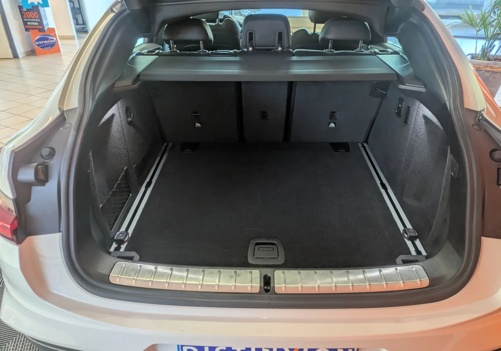 Coffre ouvert vu de l'arrière d'un BMW X4 blanc 2021, montrant un espace de chargement propre et bien agencé.