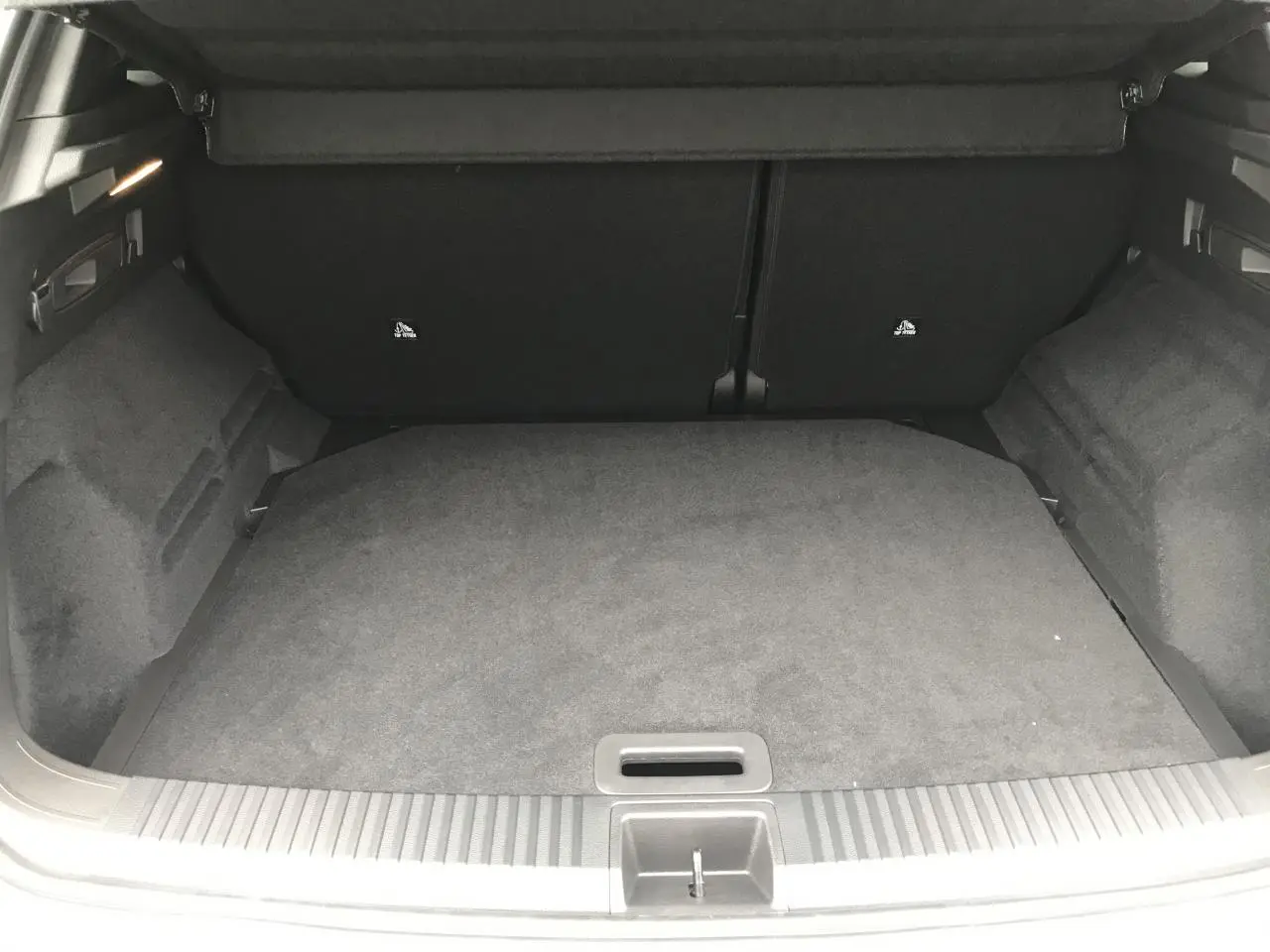 Coffre ouvert du Renault Austral blanc, vue intérieure montrant le plancher plat et les côtés garnis de tissu noir.