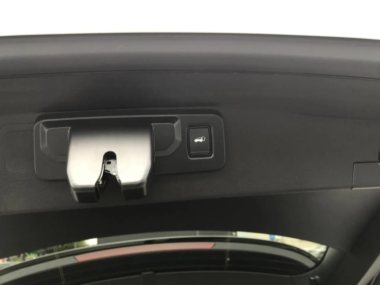 Détail du mécanisme d'ouverture du hayon motorisé noir sur Renault Austral blanc, vue intérieure du coffre.