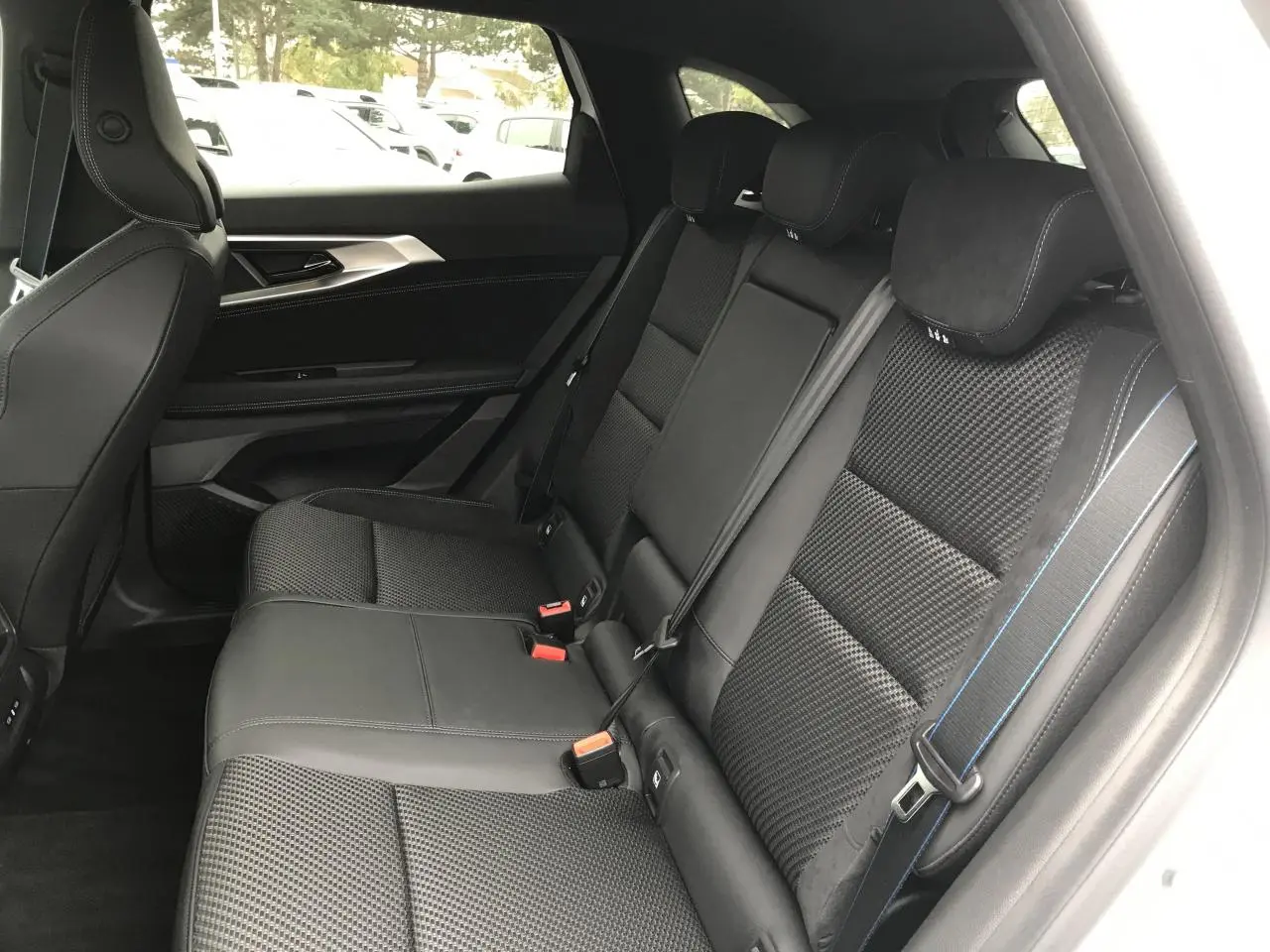 Vue intérieure côté droit des sièges arrière noirs en tissu carbone alcantara avec surpiqûres bleu blanc rouge du Renault Austral 2025.